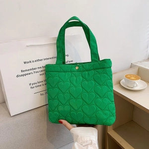 Detail of green quilted tote bag with heart patterns and gold snap button closure