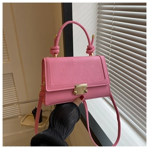 Detail of pink croc-embossed small handbag featuring gold buckle and knotted handle
