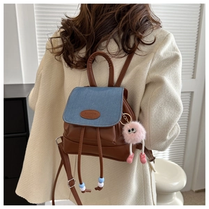 Detail view of mini vintage backpack with brown leather body and blue denim flap texture