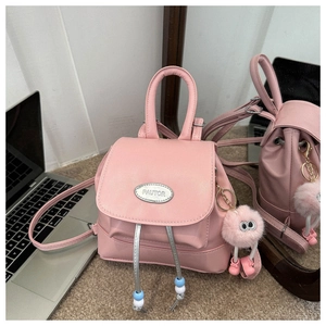 Detail of pink faux leather mini backpack with beaded drawstring and plush monster charm