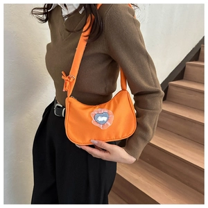 Detail of orange nylon hobo bag featuring a heart-shaped rabbit patch and lace trim