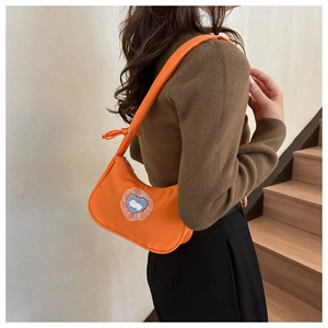 Detail of orange underarm bag with a lace heart rabbit patch and nylon texture