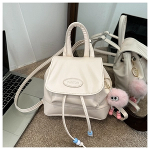 Detail view of cream white mini backpack with PAUTOR logo and cute plush ball charm