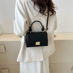 Minimalist black leather crossbody bag with crocodile texture and gold hardware on model