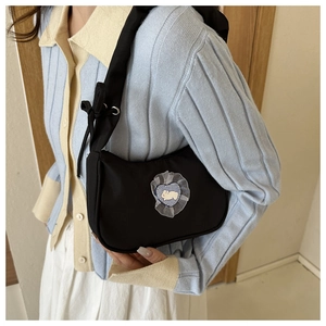 Detail of black nylon underarm bag featuring a cute heart-shaped lace rabbit patch