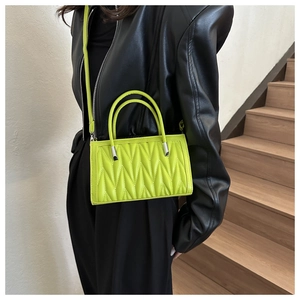 Dettaglio della borsa trapuntata verde neon con hardware argento e doppi manici