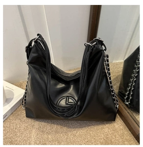Détail du sac cabas noir avec décor de chaîne en métal et logo circulaire gaufré