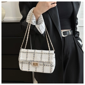 Détail du sac bandoulière en tweed avec chaîne dorée et fermoir pivotant en métal