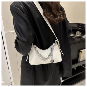 Detail view of a white PU leather crescent bag with silver chunky chain on a black jacket
