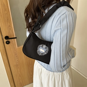 Minimalist black nylon underarm bag with blue heart rabbit patch shown from a side-rear angle