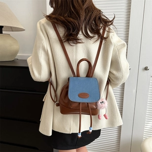 Retro mini backpack in brown leather and blue denim with a pink plush charm accessory