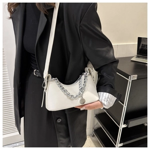 Detail view of a white crescent crossbody bag with silver chain and round metal pendant