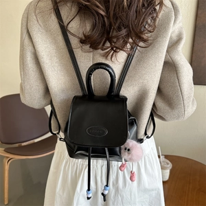 Retro black leather mini backpack with a pink plush charm and metal logo on the flap