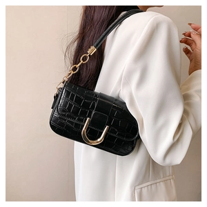 Close-up of black crocodile pattern shoulder bag with gold U-shaped buckle and chain strap