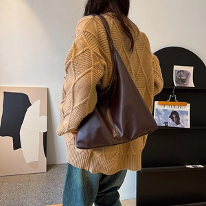 Large dark brown minimalist leather tote bag styled with a casual sweater and jeans