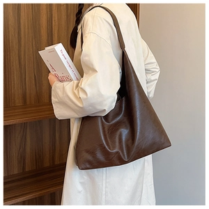 Vue détaillée d'un grand sac cabas marron porté à l'épaule par un mannequin pour femme