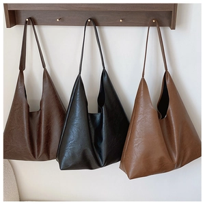 Trois sacs cabas en cuir PU texturé en marron, noir et café suspendus au rack