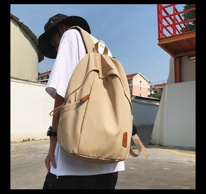 Detail view of khaki nylon backpack on model showing large capacity and side pocket