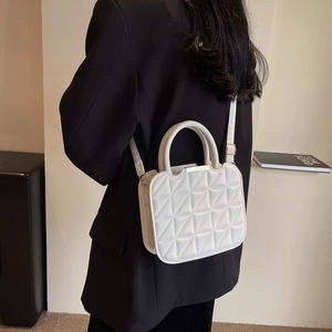 Chic white quilted handbag with a unique triangular pattern and adjustable strap