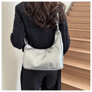 Silver crescent underarm bag in shiny metallic finish shown from a back view on model