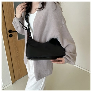 Detail of black crescent shoulder bag featuring scrunchie strap and elegant bow knots