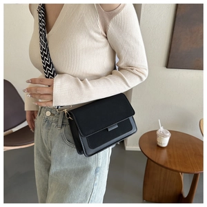 Detail of minimalist black crossbody bag with decorative black and white zigzag strap