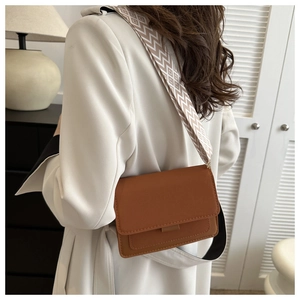 Brown leather crossbody bag detail with elegant geometric diamond pattern wide strap