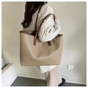 Dettaglio della grande borsa tote intrecciata indossata con un maglione beige