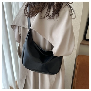 Minimalist black faux leather large crescent hobo bag styled with a beige trench coat