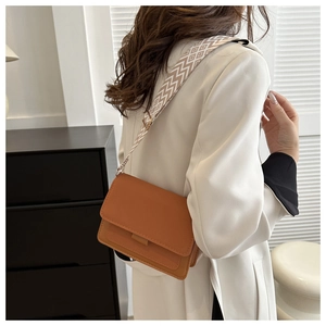 Detail view of caramel faux leather crossbody bag with geometric pattern wide strap