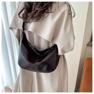 Detail view of a large dark brown hobo bag worn with a beige trench coat for a chic look