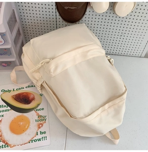 Detailansicht des cremefarbenen Nylon-Rucksacks mit Kordelzug und Reißverschluss