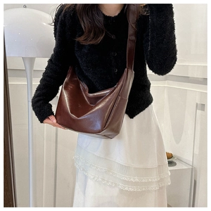 Detail of glossy brown oil leather underarm bag highlighting texture and craftsmanship