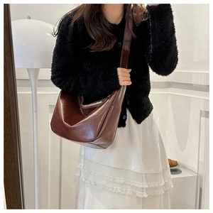 Brown glossy leather shoulder bag with wide strap and zip closure on female model