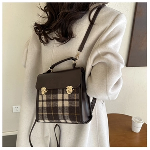Detail view of British style vintage plaid backpack with brown leather flap on a model coat