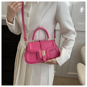 Détail du sac à main rose foncé avec coutures fines et boucle en métal doré sur costume blanc