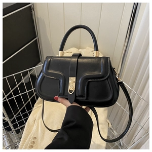 Détail d'un sac à main noir structuré avec surface texturée et fermoir en métal doré