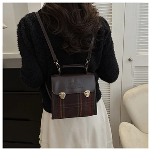 Retro plaid backpack in red and green tweed with dark brown leather flap worn by a model