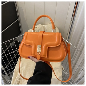 Détail du sac à main orange vif avec relief géométrique et fermoir en métal doré