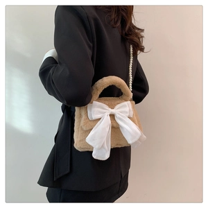 Détail du sac en peluche marron clair avec nœud en soie blanc et chaîne en perles