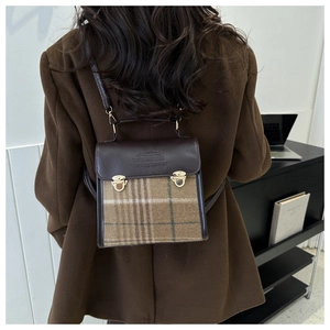 Detail of vintage brown plaid backpack with leather flap and gold metal buckles on a model