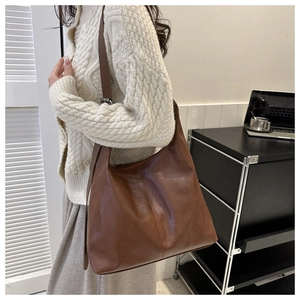 Detail of a brown PU leather hobo bag showing wrinkled texture and wide shoulder strap