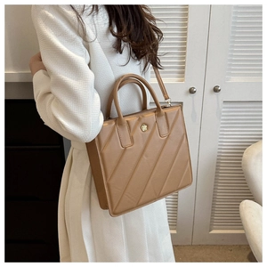 Detail view of tan crossbody bag showing quilted texture and gold camellia floral metal logo