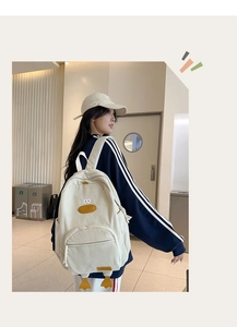 Detailed view of cream corduroy backpack featuring cute yellow duck character design