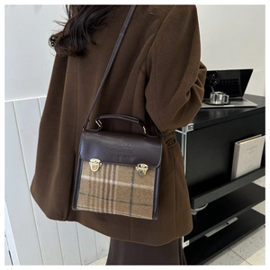 Detail shot of vintage plaid backpack with brown faux leather trim and golden buckles