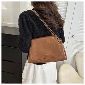 Sac fourre-tout vintage marron avec logo doré et bandoulière chaîne porté par un mannequin