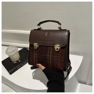 Detailed close-up of a vintage brown leather backpack with green and red plaid fabric texture