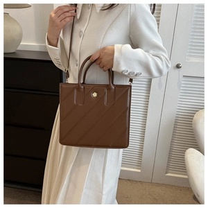 Brown leather crossbody bag detail featuring quilted texture and golden flower logo
