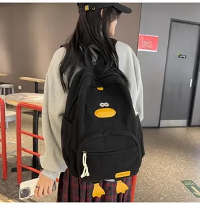Detail of black corduroy cartoon duck backpack with yellow pockets on a model