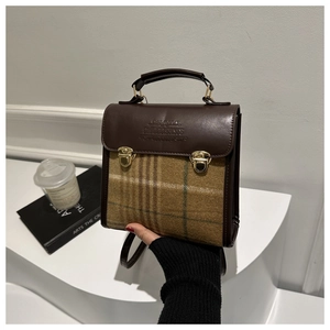 Detail of vintage patchwork backpack showing brown leather and plaid fabric texture